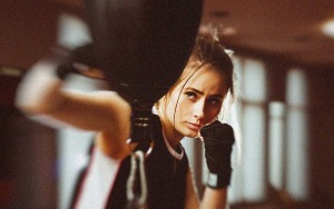 active young woman, focused during non-contact boxing training in a gym